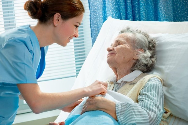 Nurse cares for a elderly woman lying in bed