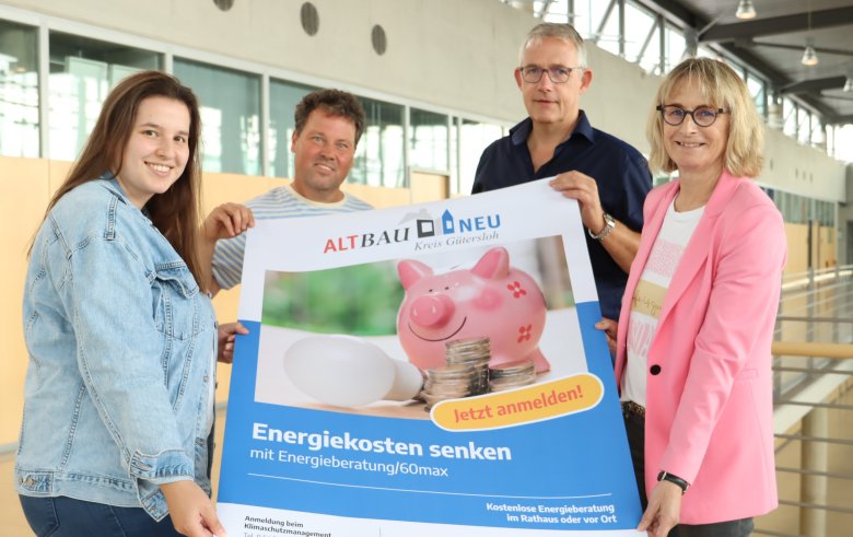 4 Personen stehen im Foyer des Kreishauses Gütersloh und halten ein Werbeplakat in den Händen.