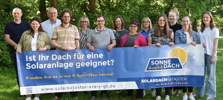 Personen stehen - teils zweireihig - nebeneinander und halten einen Banner zum Solardachkataster in den Händen. 