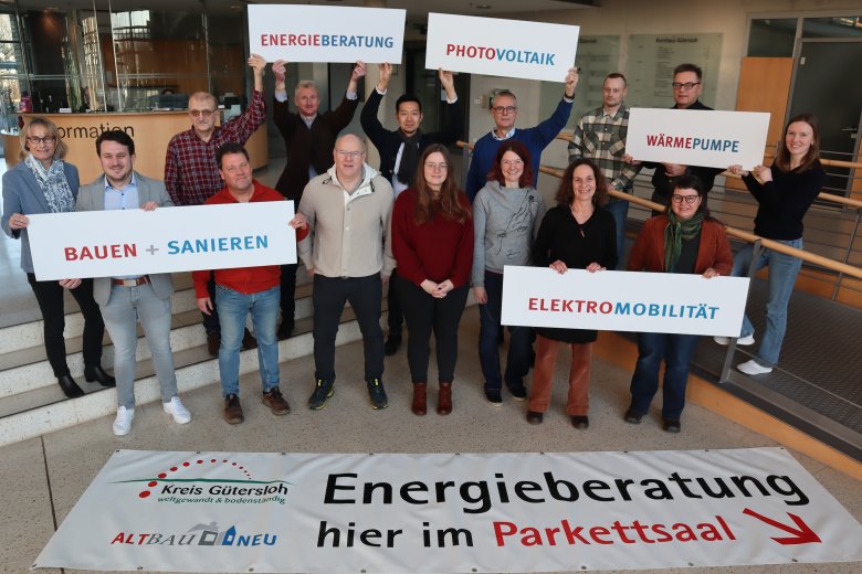 Auf dem Bild sind Frauen und Männer zu sehen, die Plakate in den Händen halten und Werbung für den Informationsstand der ALTBAUNEU-Initiative auf der Baumesse machen.