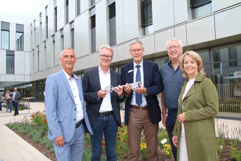 Fünf Personen stehen vor dem neuen Kreishaus und halten einen symbolischen Schlüssel in der Hand.