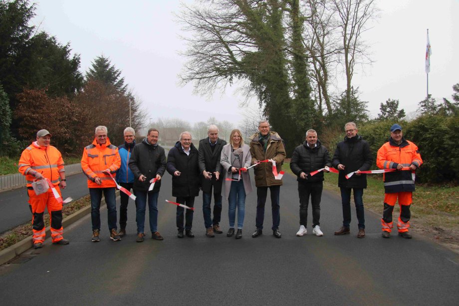 Zwölf Personen durchschneiden ein rot-weißes Flatterband auf der Vennorter Straße bei der offiziellen Freigabe für den Verkehr.