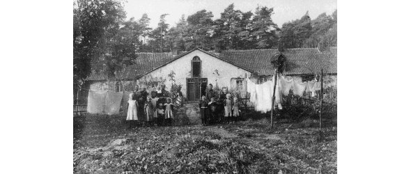 Werkswohnung der Holter Eisenhütte, das sog. Familienhaus. Hier wohnten sechs Familien auf engstem Raum. Aufnahme aus dem Jahr 1909 mit Familien vor der Werkswohnung.